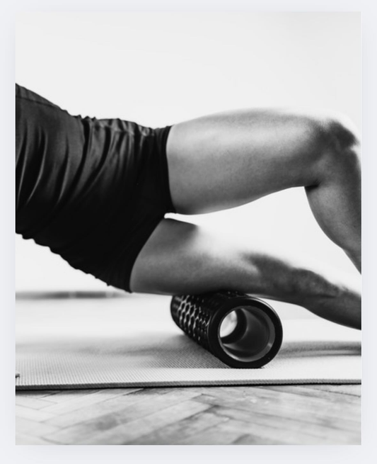 Close-up of a person using a foam roller on the thigh.