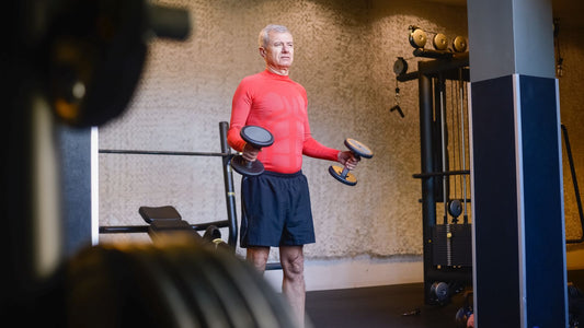 An older man exercising with dumbbells indoors.